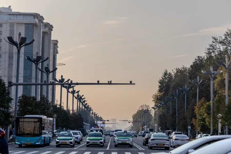 Широкий городской проспект с плотным автомобильным потоком и автобусом на закате